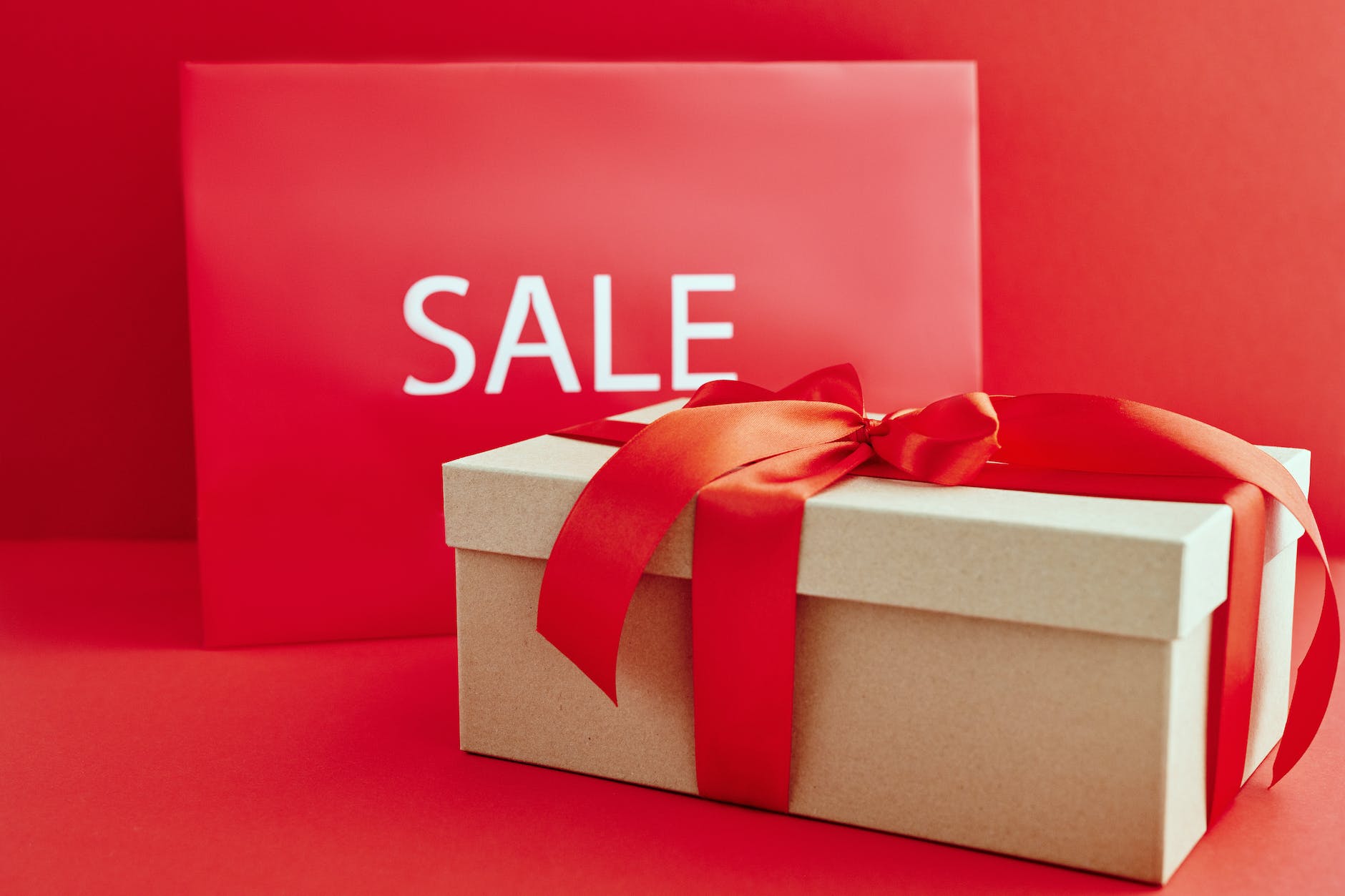 cardboard box with red ribbon beside a sale sign